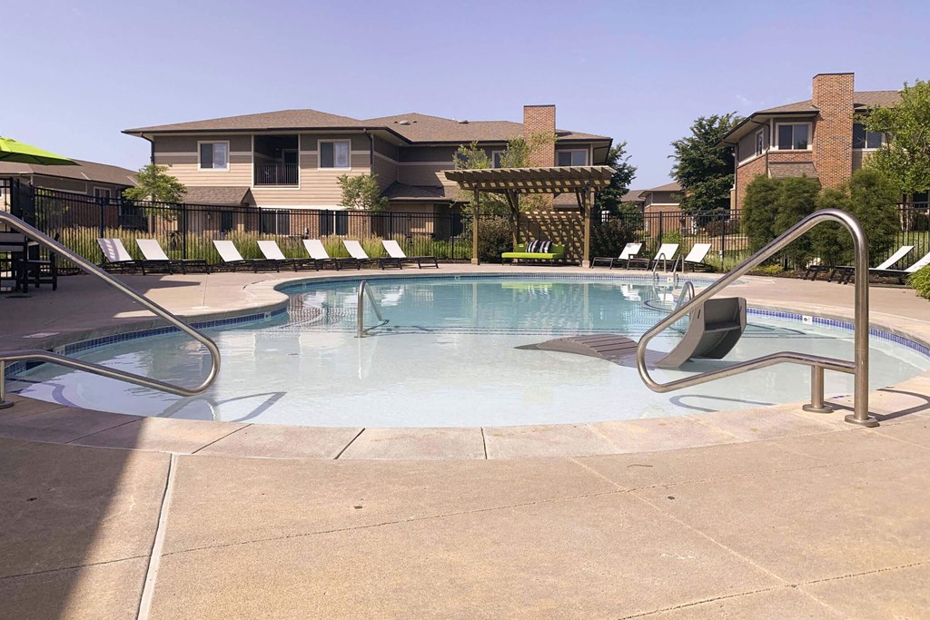 a swimming pool with chairs around it and a building in the background