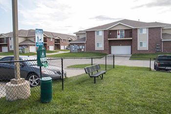 an off leash dog park with a bench and a trash can with doggy bags