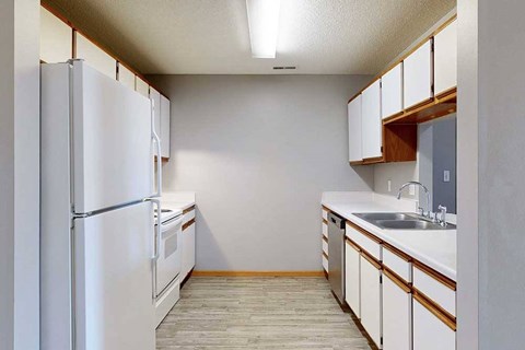A kitchen with a white refrigerator and white cabinets.