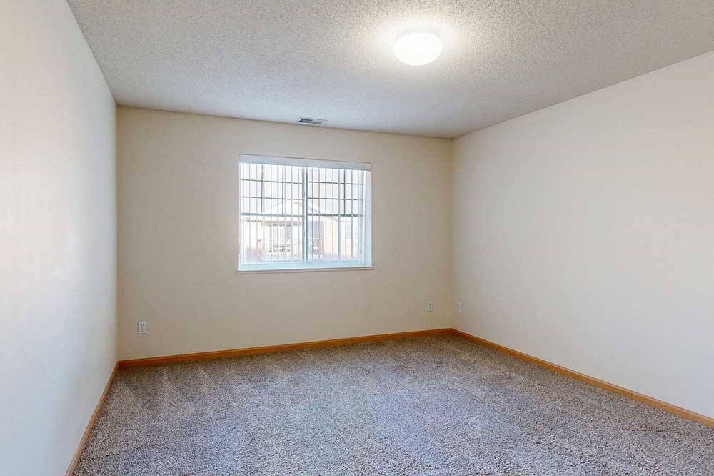 Empty room with a window and a carpeted floor.