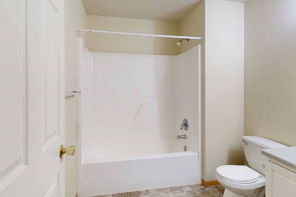 A white bathroom with a toilet and a bathtub.