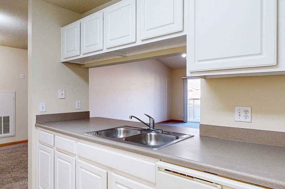 A kitchen with white cabinets and a stainless steel sink.