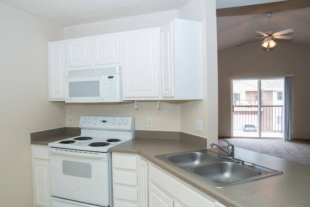 an empty kitchen with white appliances and a sink