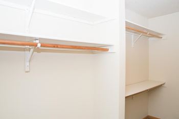a walk in closet in an empty room with white walls