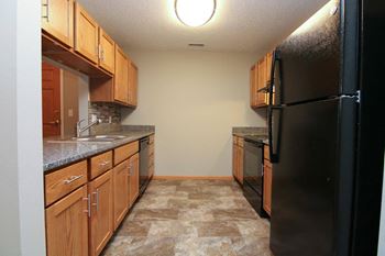 a kitchen with wooden cabinets and a black refrigerator