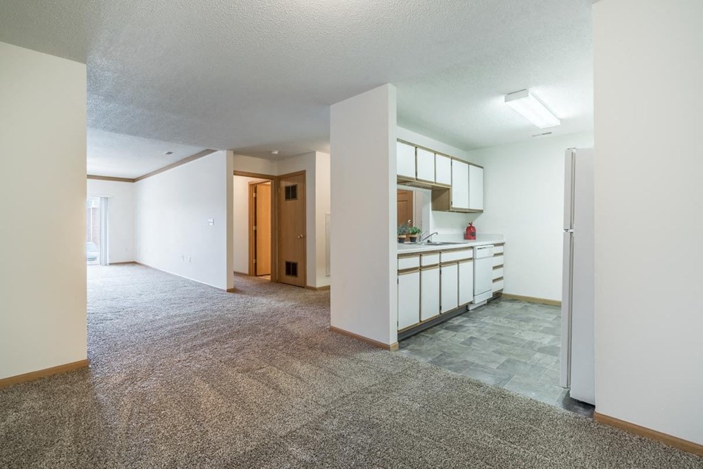 an empty living room and kitchen with a refrigerator