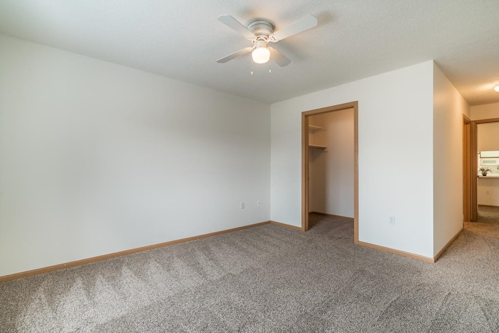 an empty living room with a ceiling fan and a closet