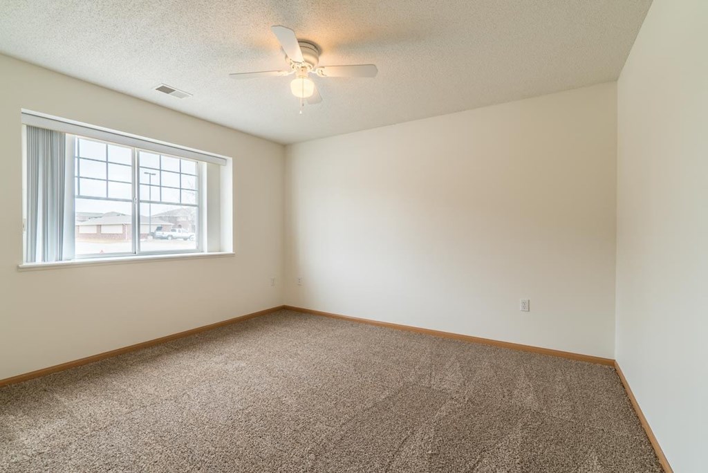 an empty room with a window and a ceiling fan