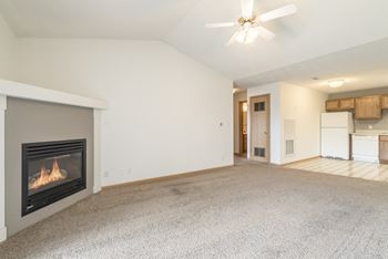 an empty living room with a fireplace and a kitchen