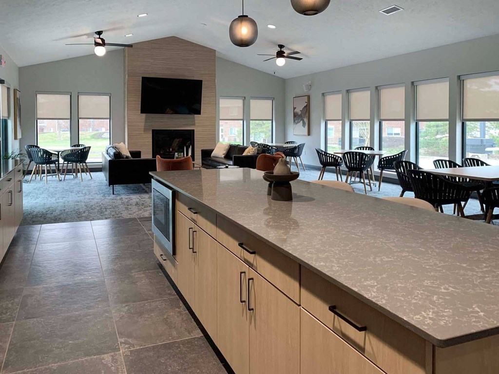 a large kitchen with a center island and a community room with a fireplace