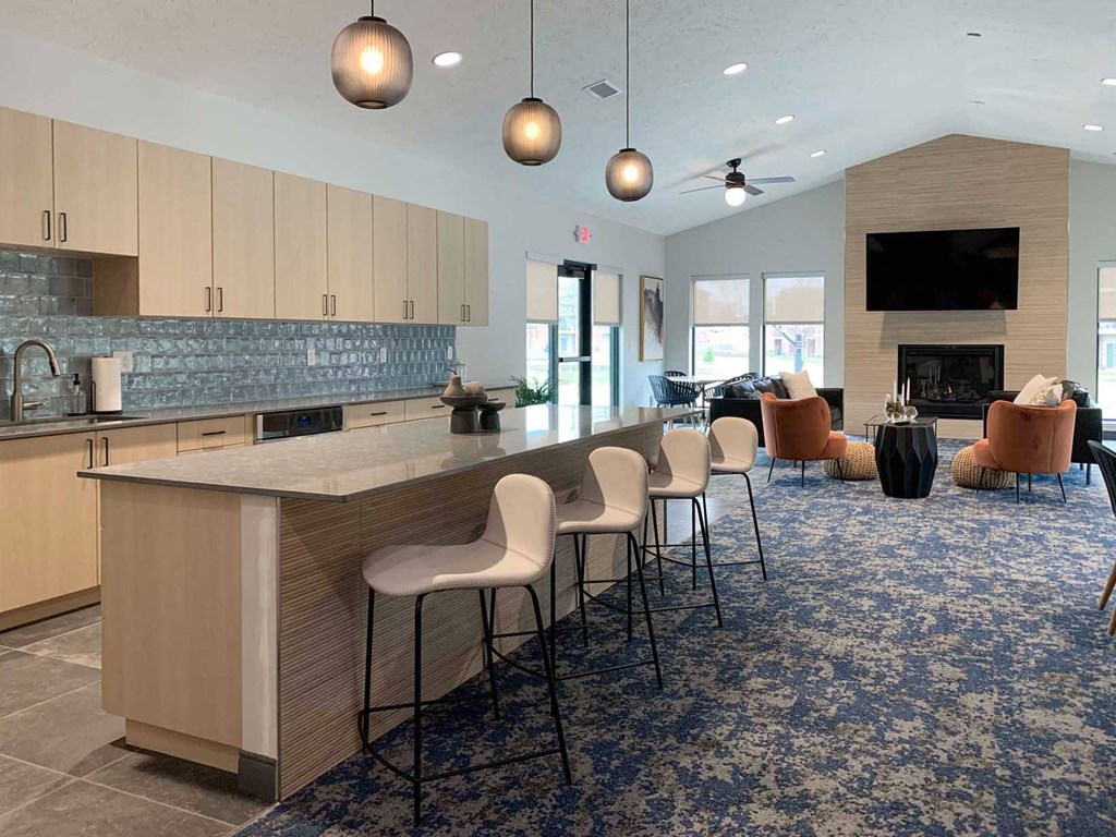 a large kitchen with a bar and a clubhouse community room with a fireplace