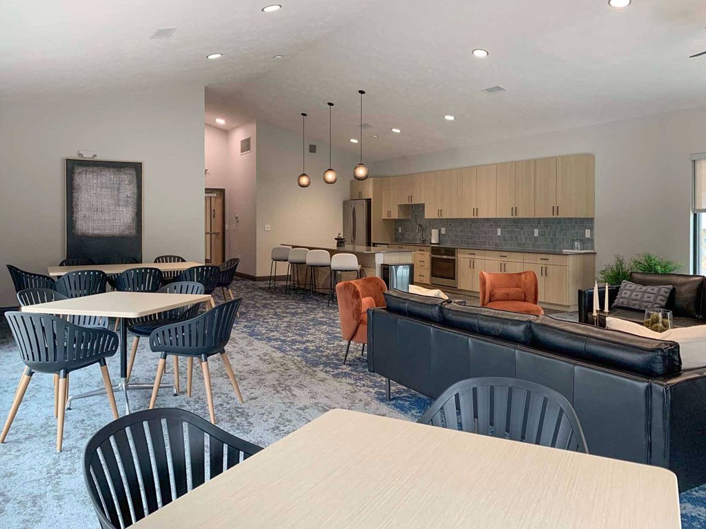 a large community room with tables and chairs and a kitchen