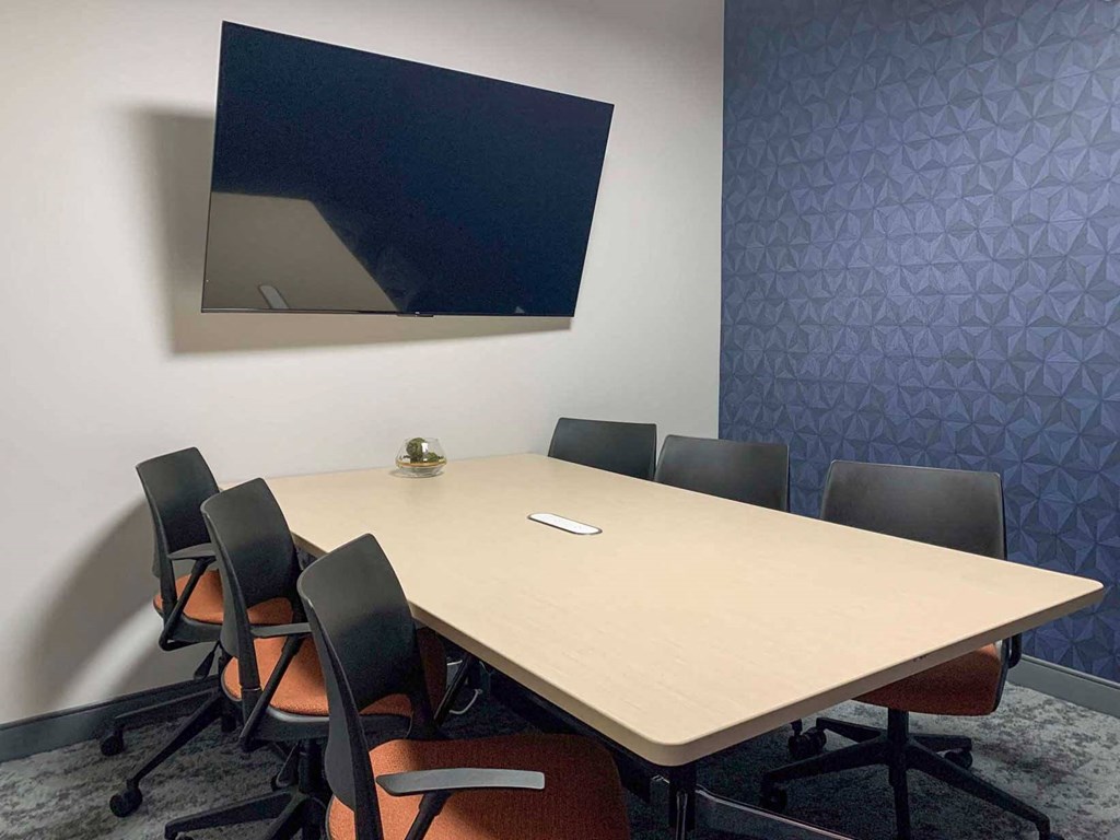 a clubhouse conference room with a table and chairs and a tv