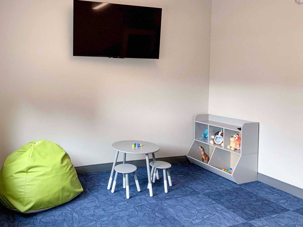 a children's area within the fitness center with a table and chairs and a television