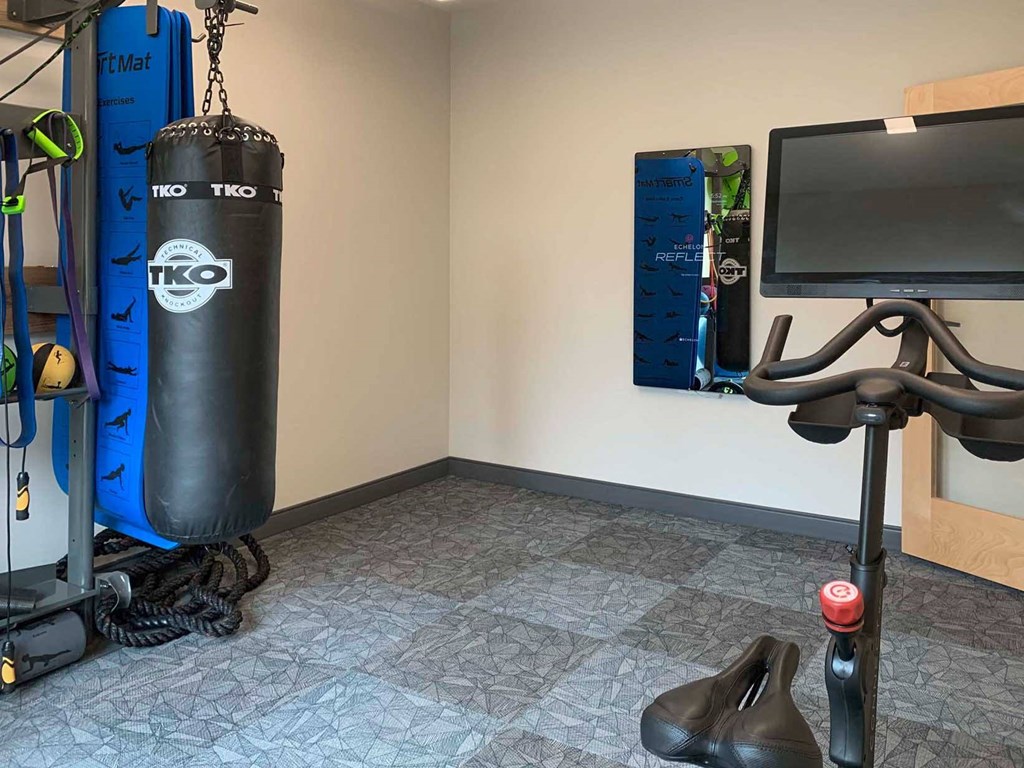 a corner of a gyp with punching bag, fitness mirror, and spin bike