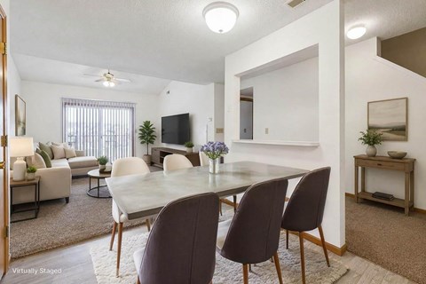 Open-concept apartment dining and living area with modern kitchen, white cabinetry, wood-style flooring, and breakfast bar seating.