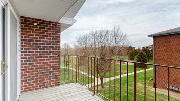 A balcony with a brick wall and a metal railing.