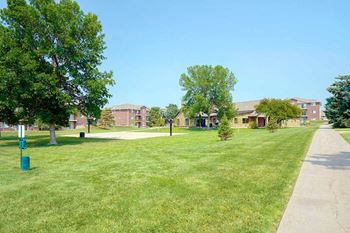 Expansive green lawn with walking paths and apartments in the background