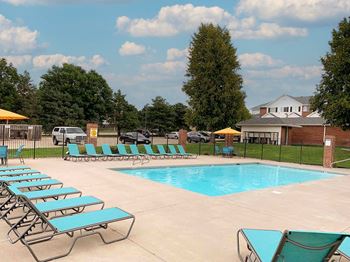 A pool with sun loungers and a building in the background.