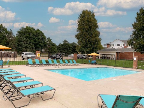 A pool with sun loungers and a building in the background.