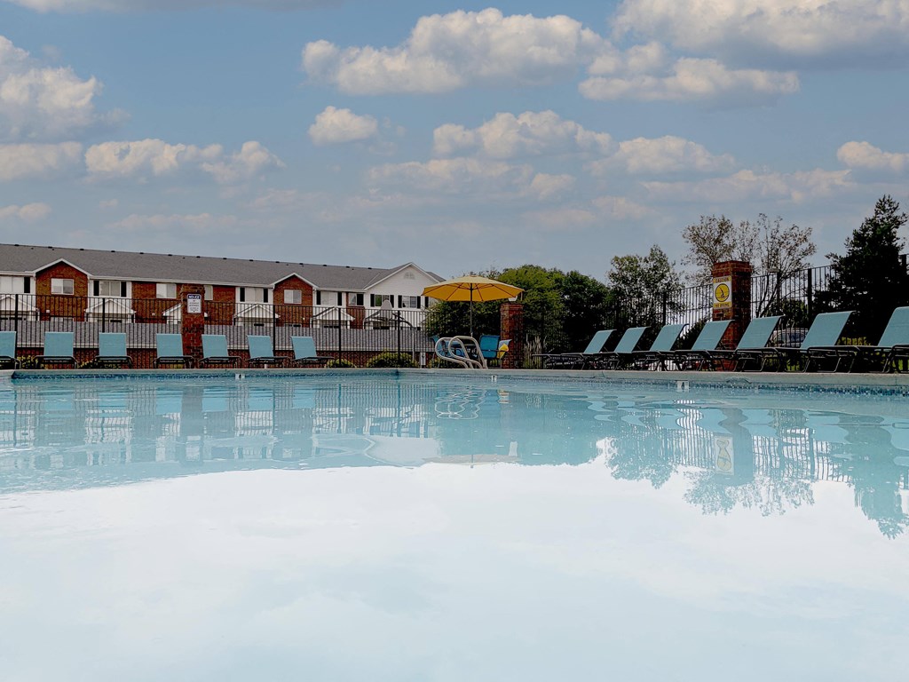 sparkling blue swimming pool with blue lounge chairs and yellow umbrella in the background