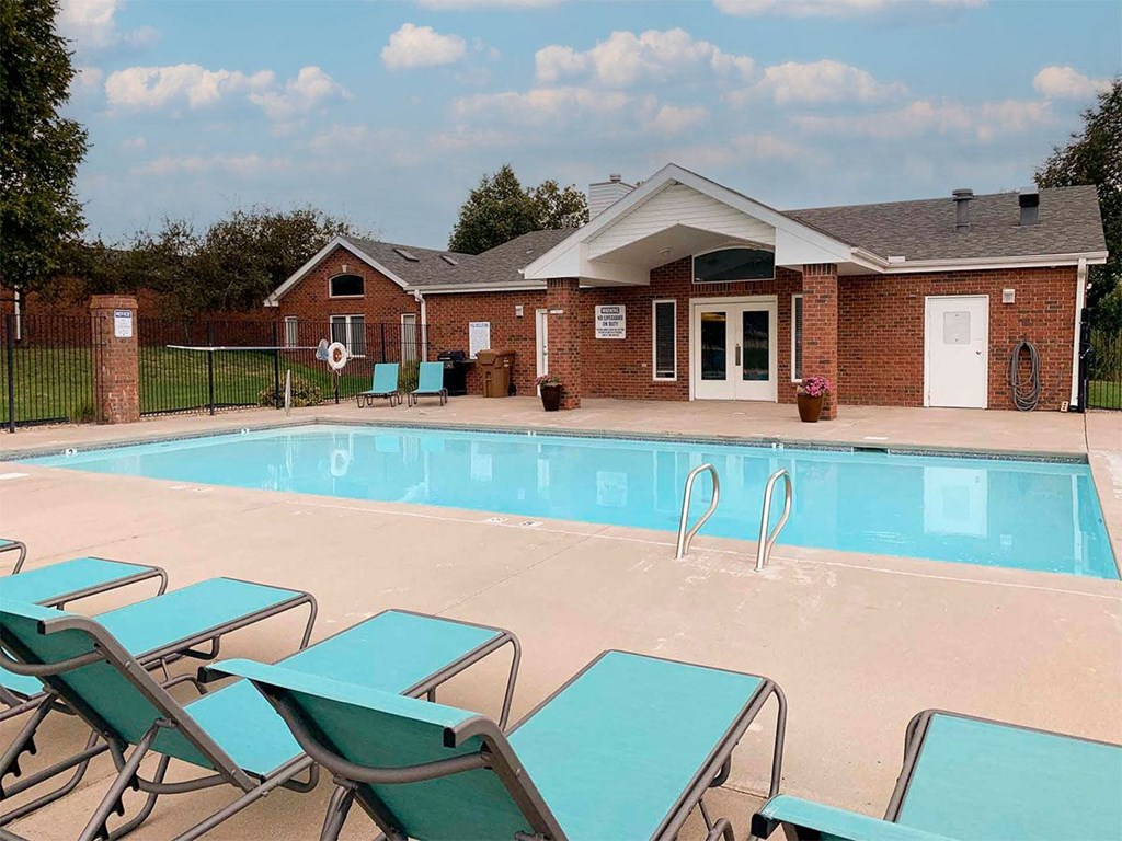A pool with loungers in front of a building.
