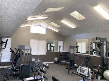 a gym with exercise machines and lights on the ceiling