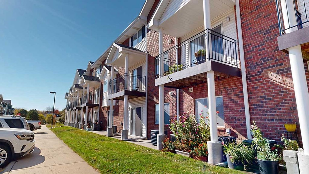a red brick apartment building with white pillars and balconies with black metal railings