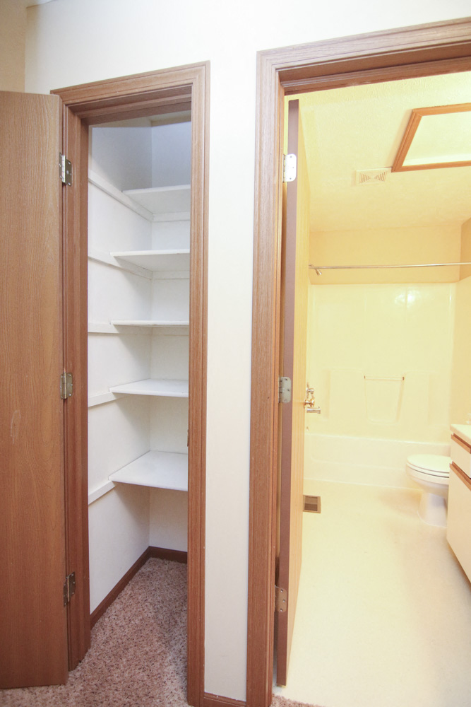 Linen closet with storage shelves next to the bathroom