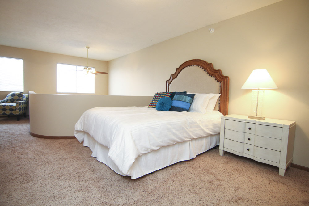 Lofted bedroom with two windows and area over looking living room below