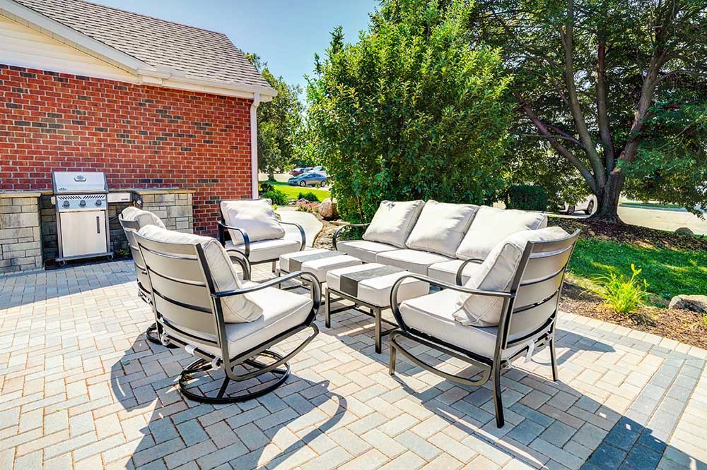 A patio with a set of white cushion chairs and a table, great for outdoor social gatherings.