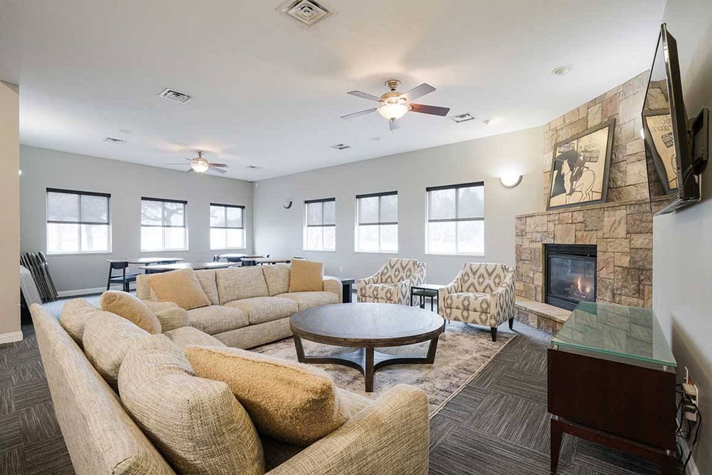 a clubhouse room with couches and a tv next to a fireplace