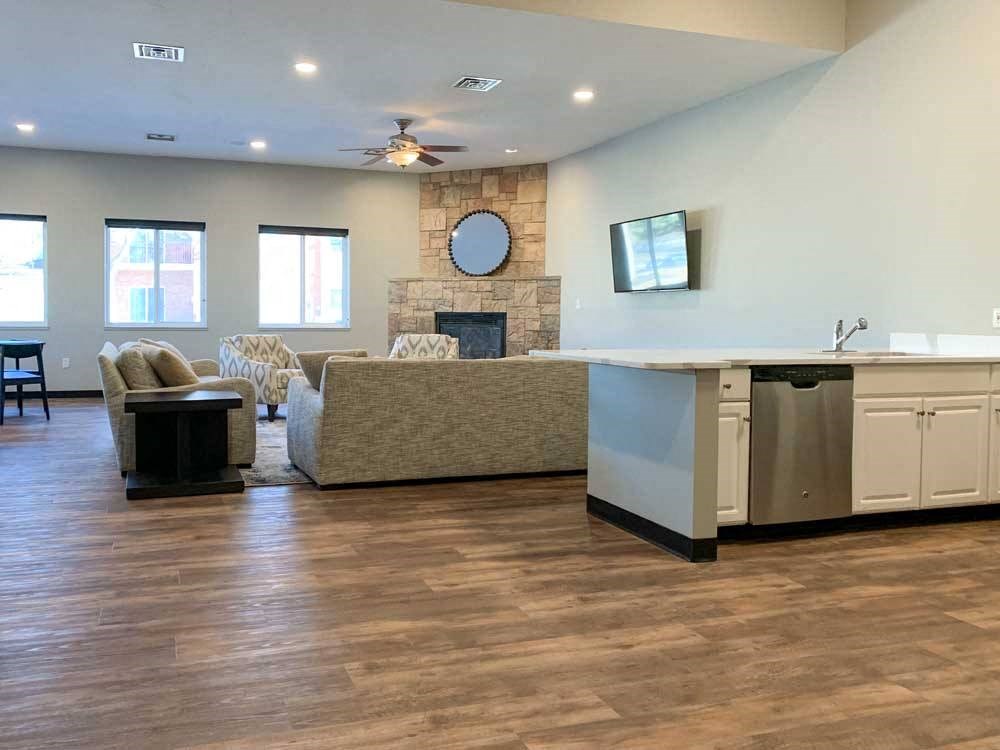 a tv lounge with a stone fire place and a grey couch, with hardwood flooring