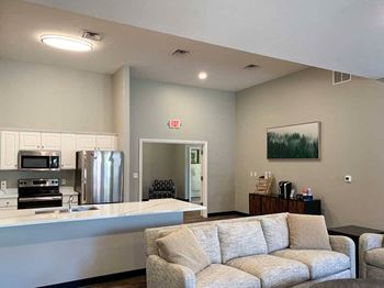 a modern kitchen with white cabinets and stainless steel appliances in a clubhosue with a coffee bar and grey couch