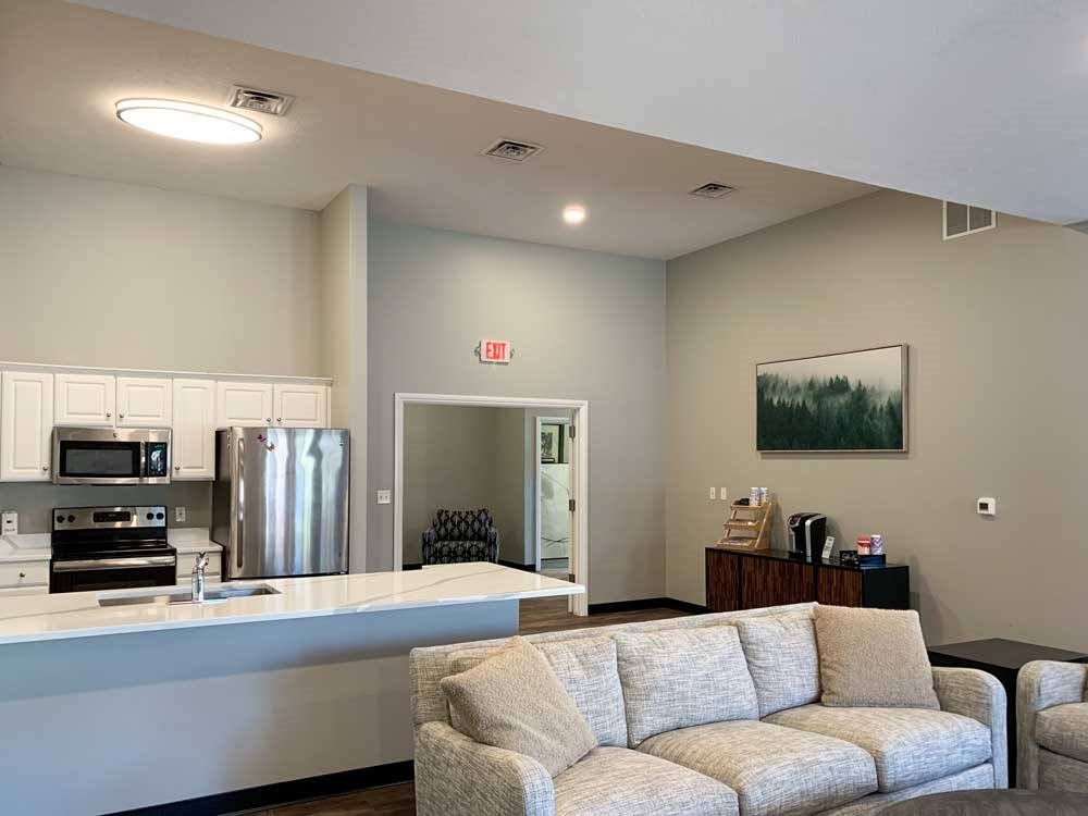 Pinebrook - Amenities - Updated Clubhouse 2025 a modern kitchen with white cabinets and stainless steel appliances in a clubhosue with a coffee bar and grey couch