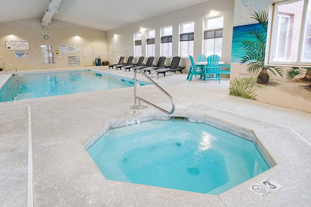 an indoor pool and hot tub with lounge chairs chairs