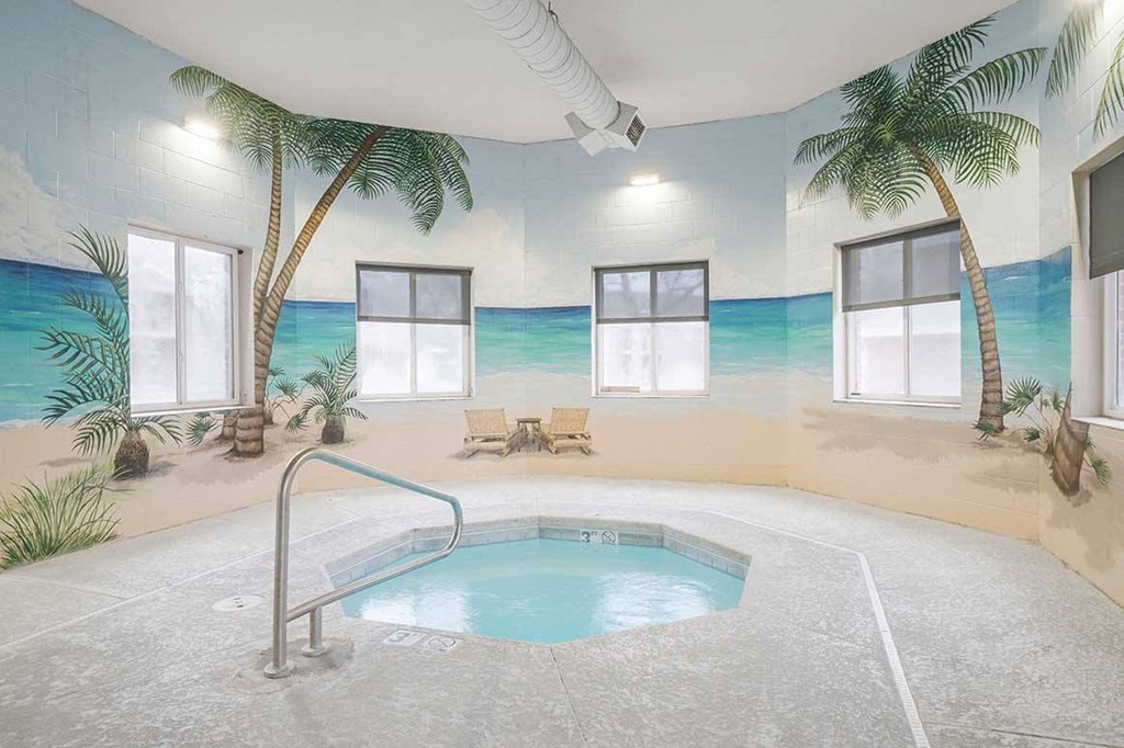 an indoor hot tub with a beach mural on the wall behind it