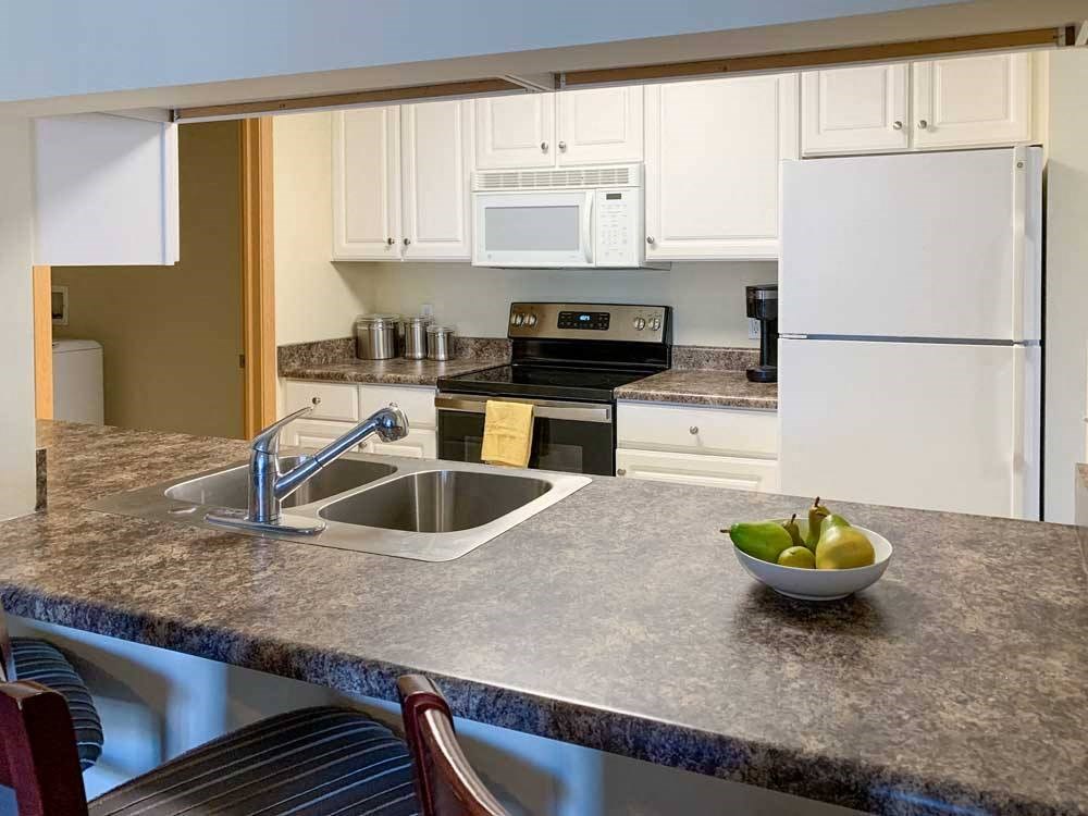 a kitchen with a bar top style counter, a sink, stove, and refrigerator