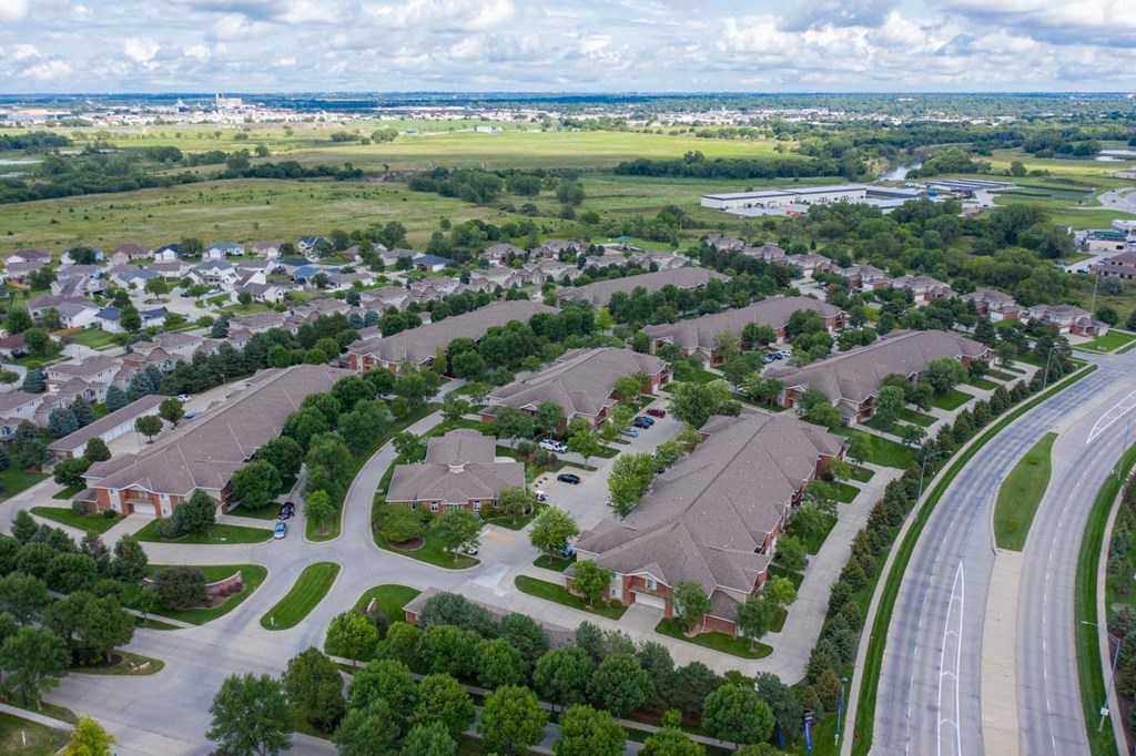 an aerial view of apartment community with multiple buildings, houses and cars
