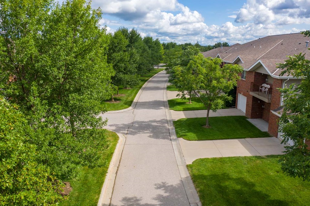 A residential street with houses on both sides and trees lining the road.