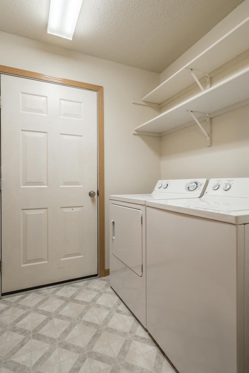 A white laundry room with a door and a washer and dryer.