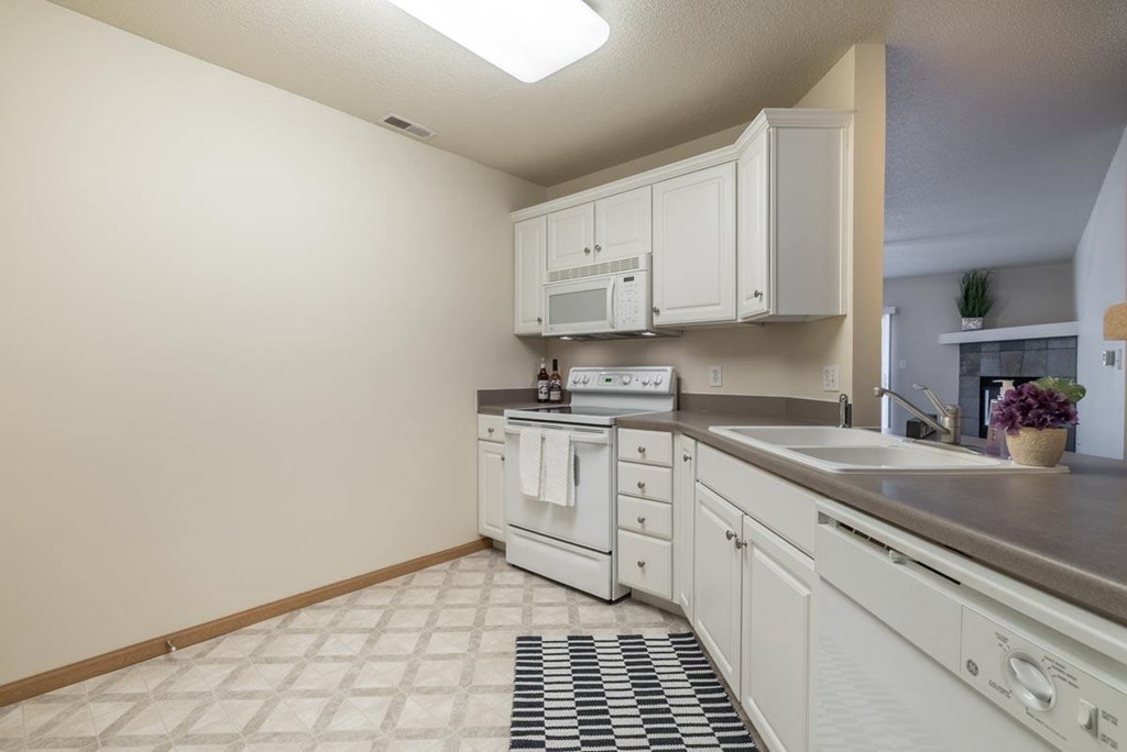 A kitchen with white cabinets and appliances.