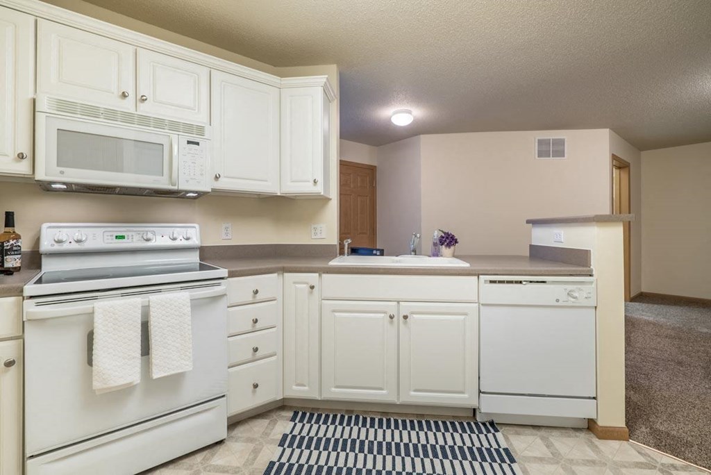 A kitchen with white appliances and cabinets.
