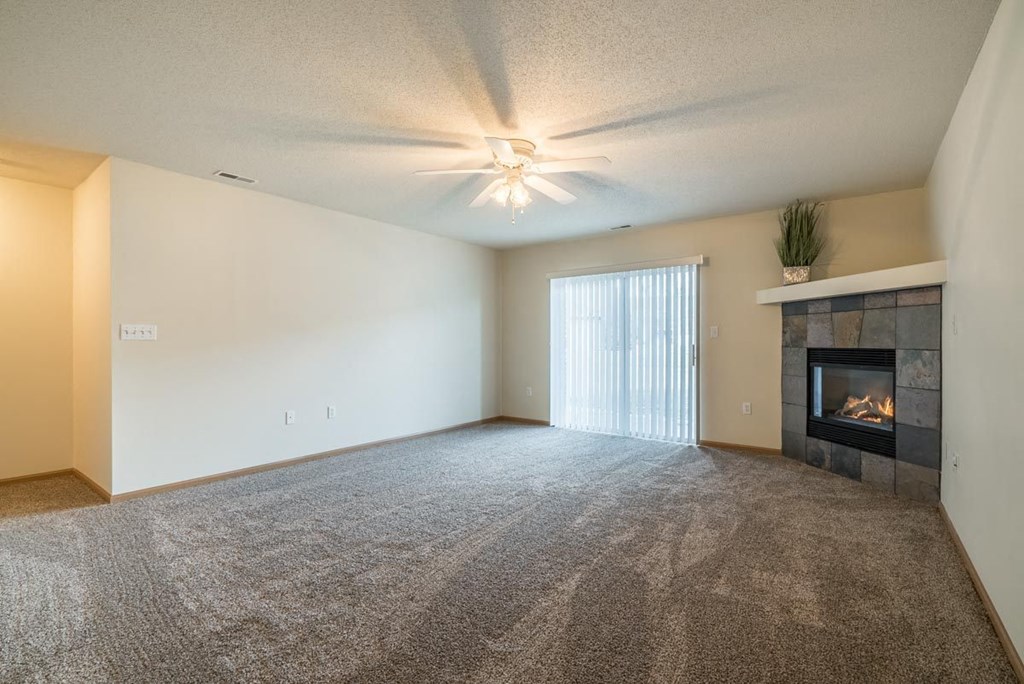 A living room with a fireplace and a ceiling fan.