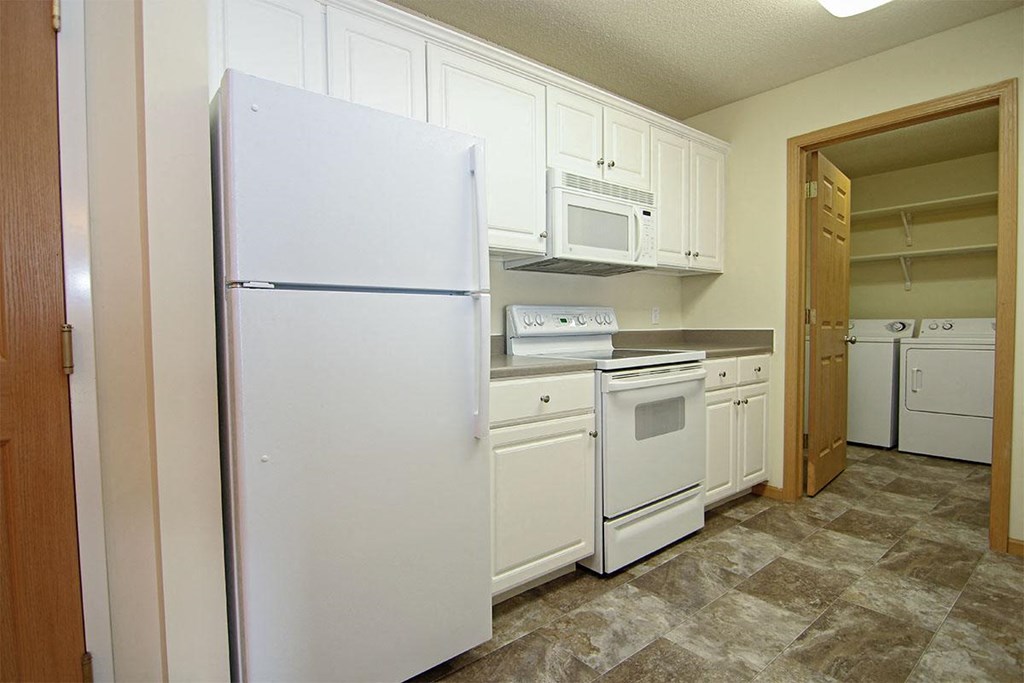A kitchen with white appliances and cabinets.
