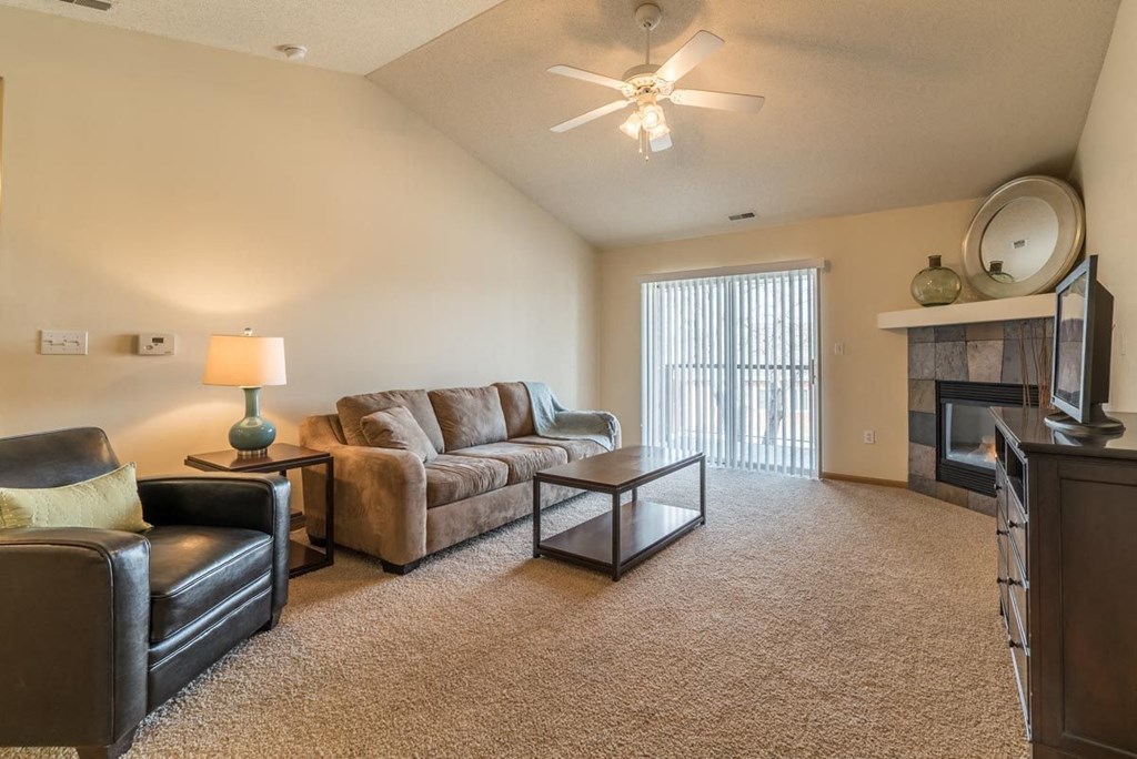 A living room with a brown couch, a black chair, and a fireplace.
