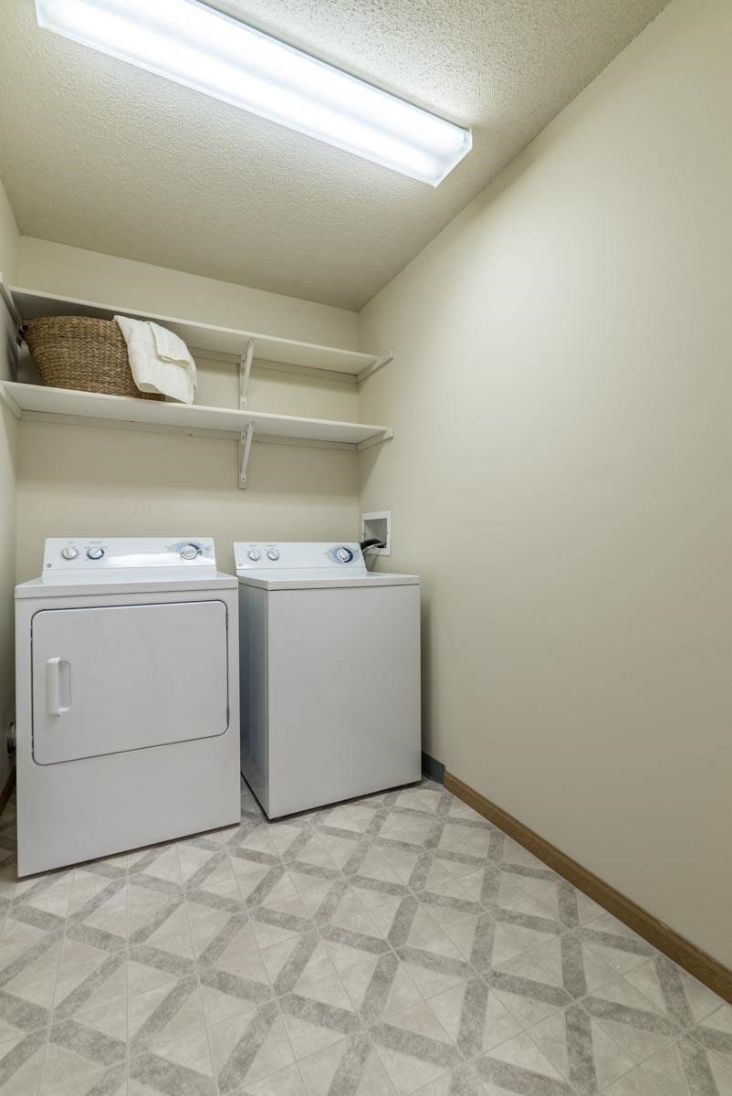 Two white washing machines in a laundry room.