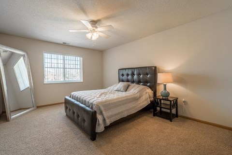 A bedroom with a bed, a nightstand, and a ceiling fan.