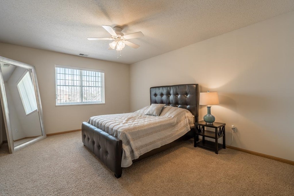 The river bedroom A bedroom with a bed, a nightstand, and a ceiling fan.