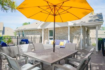 outdoor dining table and chairs shaded with a yellow umbrella on the sun deck of the community clubhouse